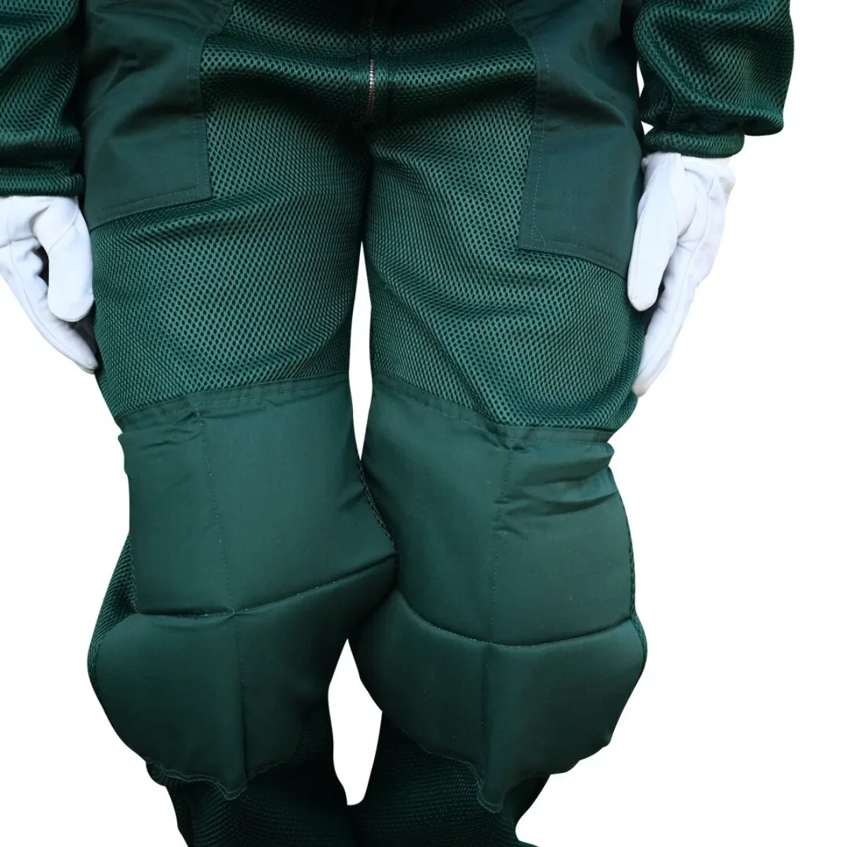 Close-up of a beekeeper's legs in a green ventilated mesh bee suit, showing the reinforced knees and room in the thigh